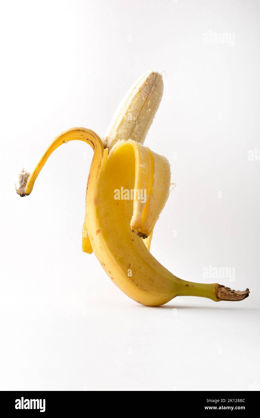 Detail of whole ripe open banana with isolated on white table. Vertical composition. Stock Photo