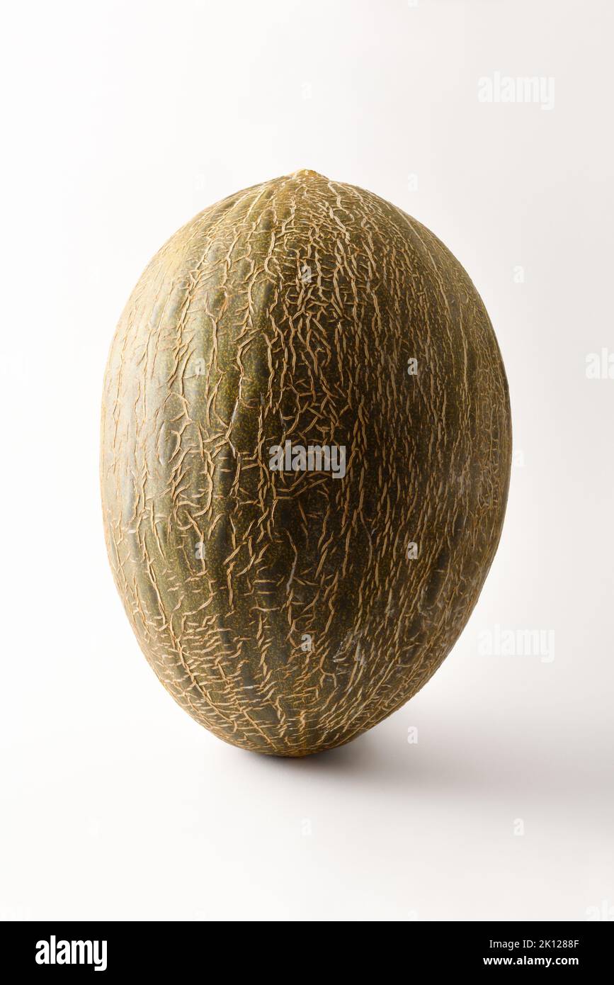 Detail of ripe green melon on white table with white isolated background. Front view. Vertical composition. Stock Photo
