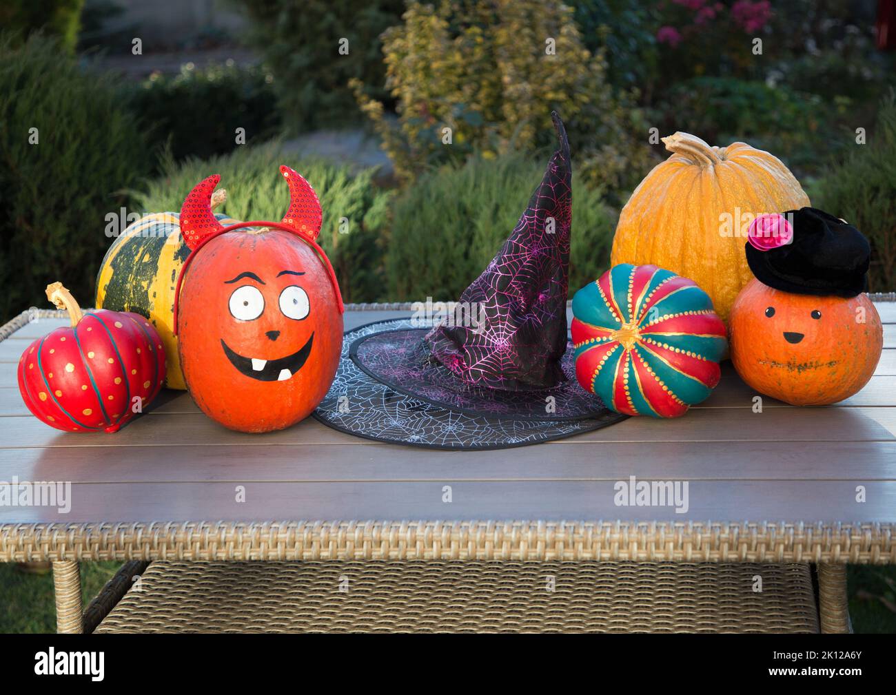 lot of various painted decorative colored pumpkins prepared for Halloween lie on the table in the garden as decoration for the holiday Stock Photo