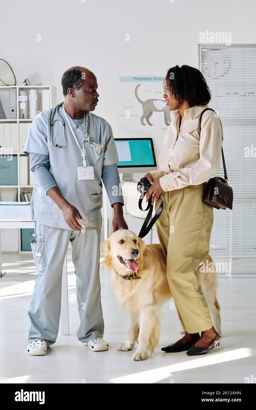 African vet doctor in uniform talking to owner of dog while they