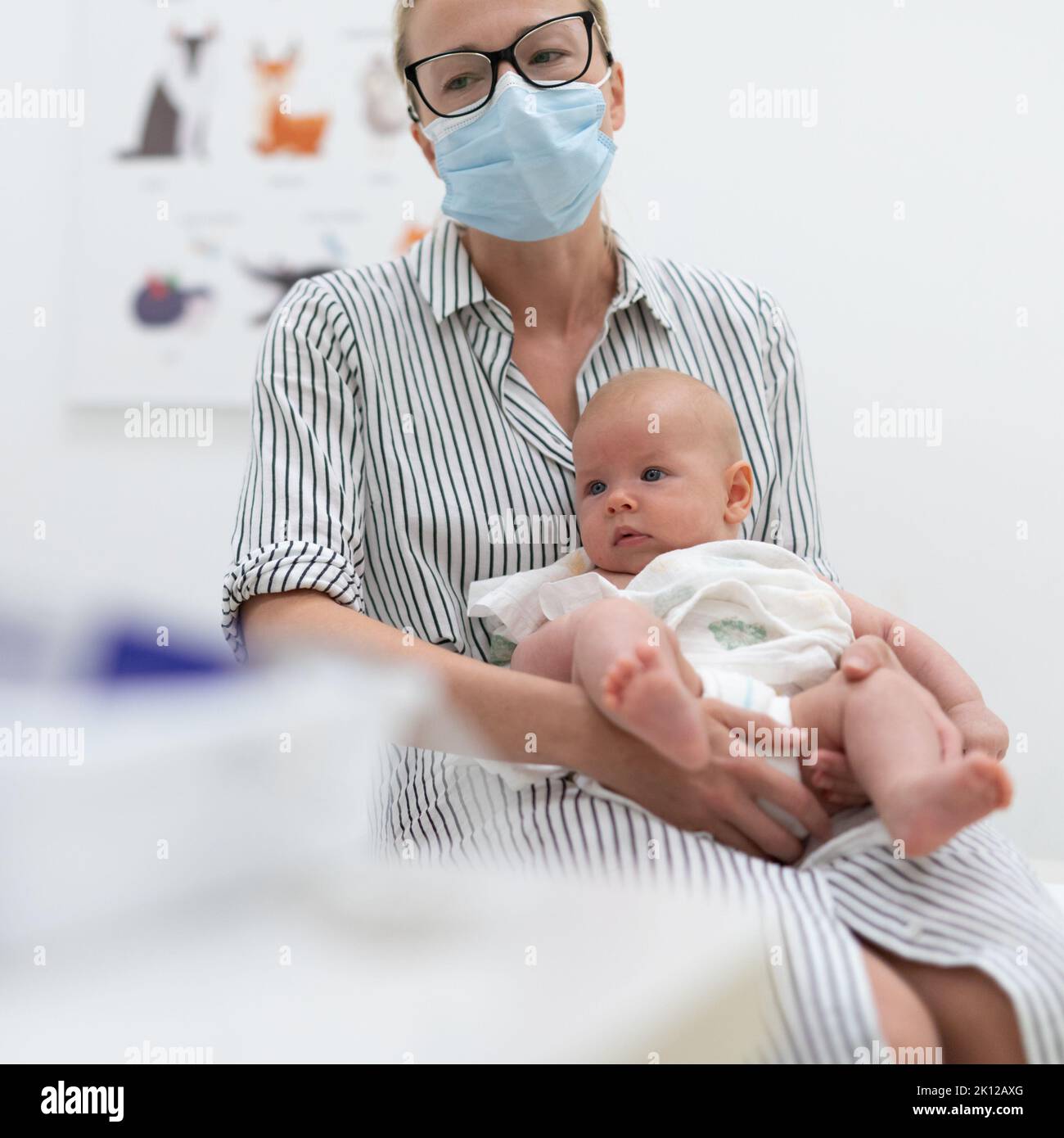 Mother holding her baby boy at medical appointment at pediatrician office. Stock Photo