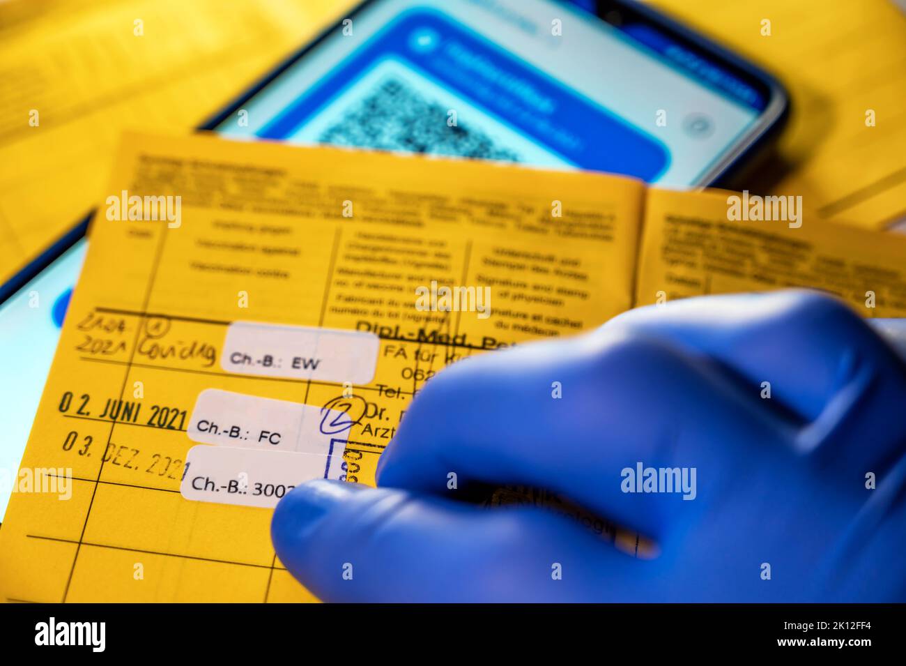 Yellow vaccination card and digital vaccination card on a smartphone Stock Photo