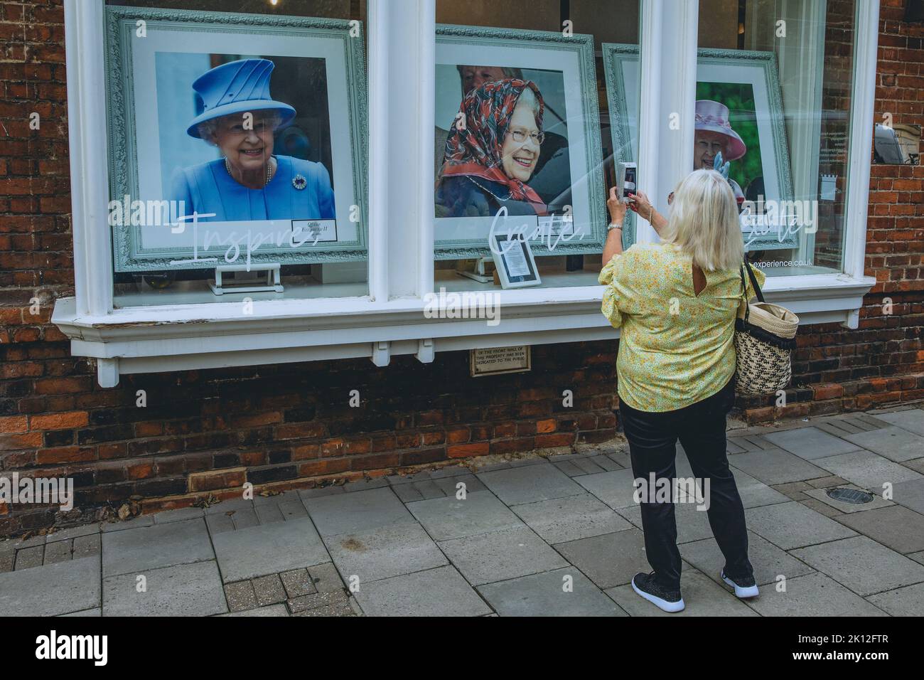 Windsor, UK. 14th September, 2022. A woman takes a photograph of portraits of Queen Elizabeth II displayed in the windows of an art gallery. Queen Elizabeth II, the UK's longest-serving monarch, died at Balmoral aged 96 on 8th September after a reign lasting 70 years and will be buried in the King George VI memorial chapel in Windsor following a state funeral in Westminster Abbey on 19th September. Credit: Mark Kerrison/Alamy Live News Stock Photo