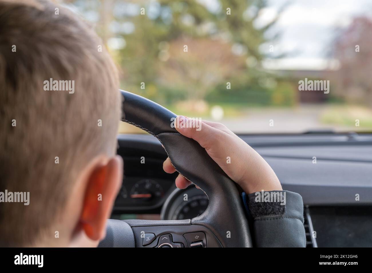 Child drives daddy's car on a street Stock Photo