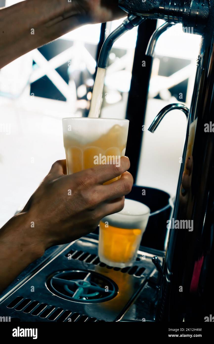 Closeup of hand serving beer in glass using tap. Bartender pouring beer