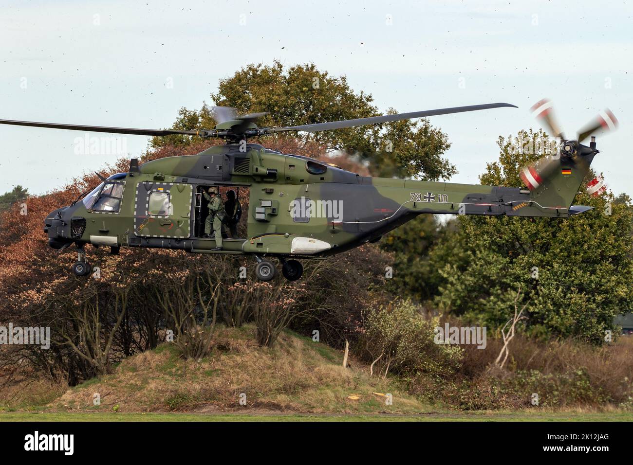 Crew chief hanging out of a German Army NH90 helicopter taking off from Deelen airbase during Falcon Autumn exercise. Deelen, The Netherlands - Octobe Stock Photo