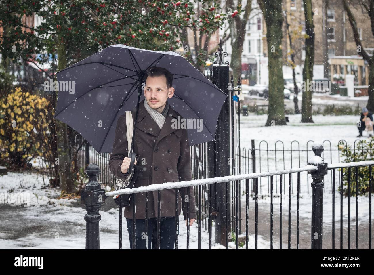 Portrait of a handsome young man with umbrella on London street in winter snow Stock Photo