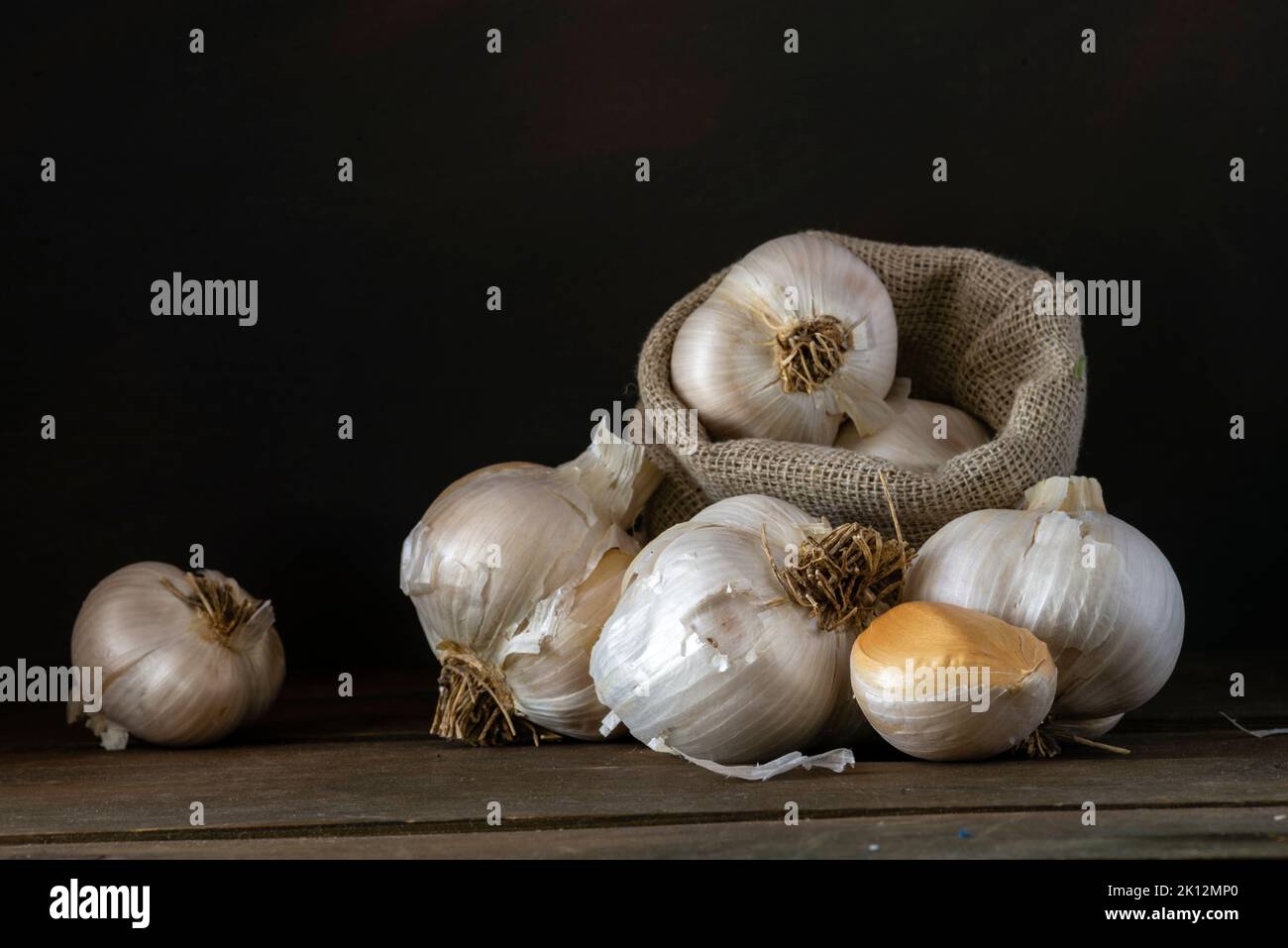big Garlic Cloves and Bulb wooden table cooking on dark background ...