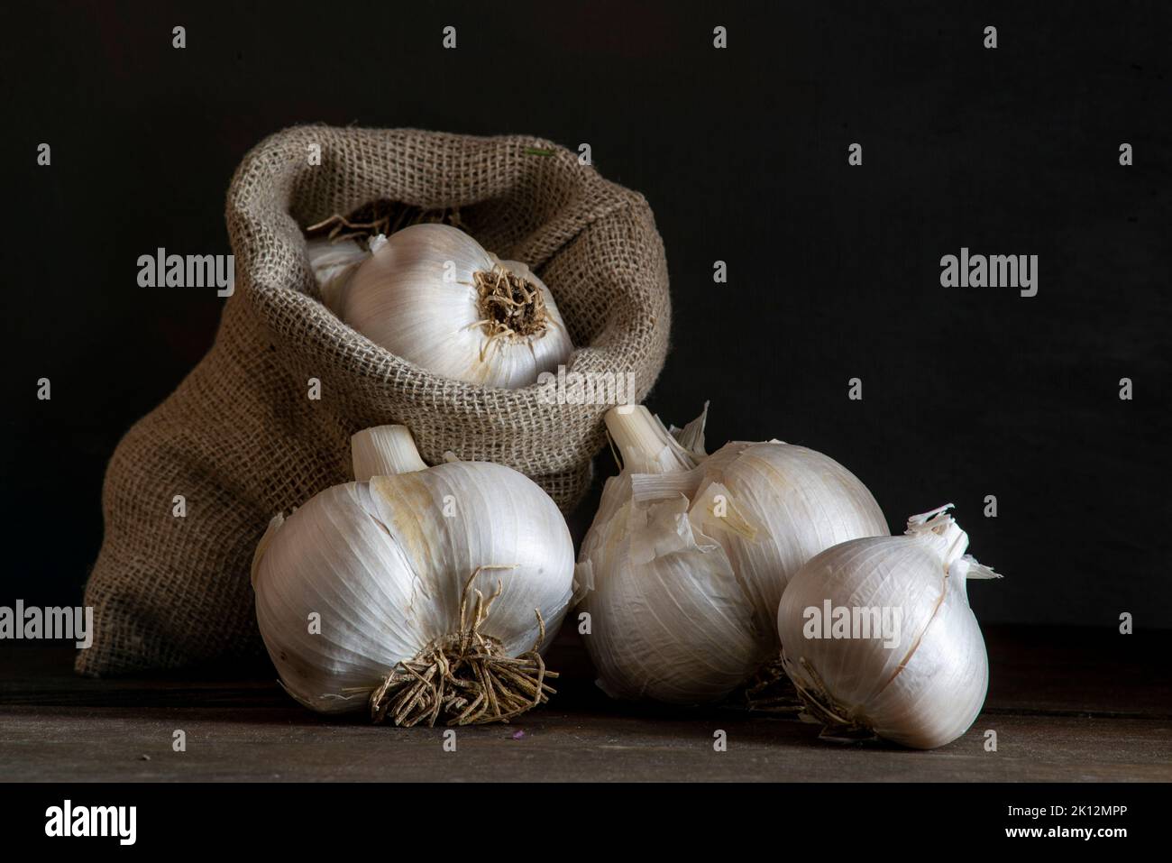 big Garlic Cloves and Bulb wooden table cooking on dark background ...