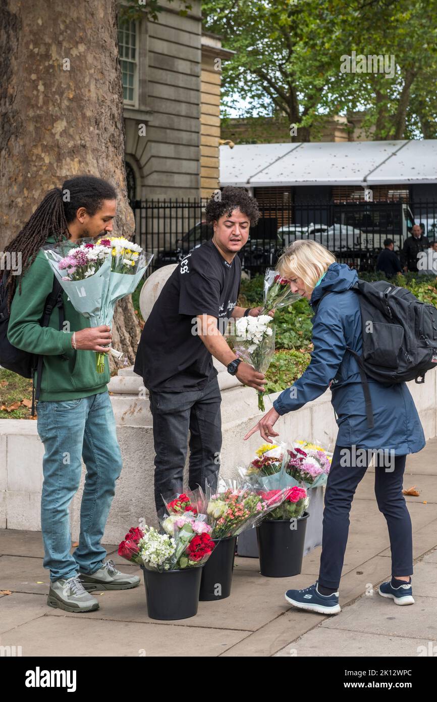 A woman buying flowers to lay outside Buckingham Palace following the death of Queen Elizabeth II Stock Photo