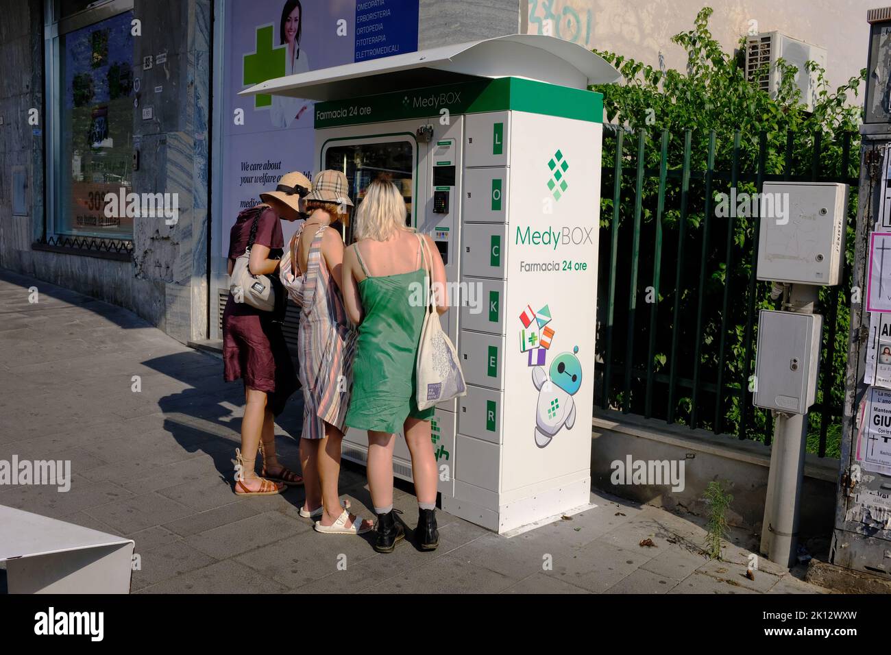 Three female tourists at a Medybox machine in Italy Stock Photo