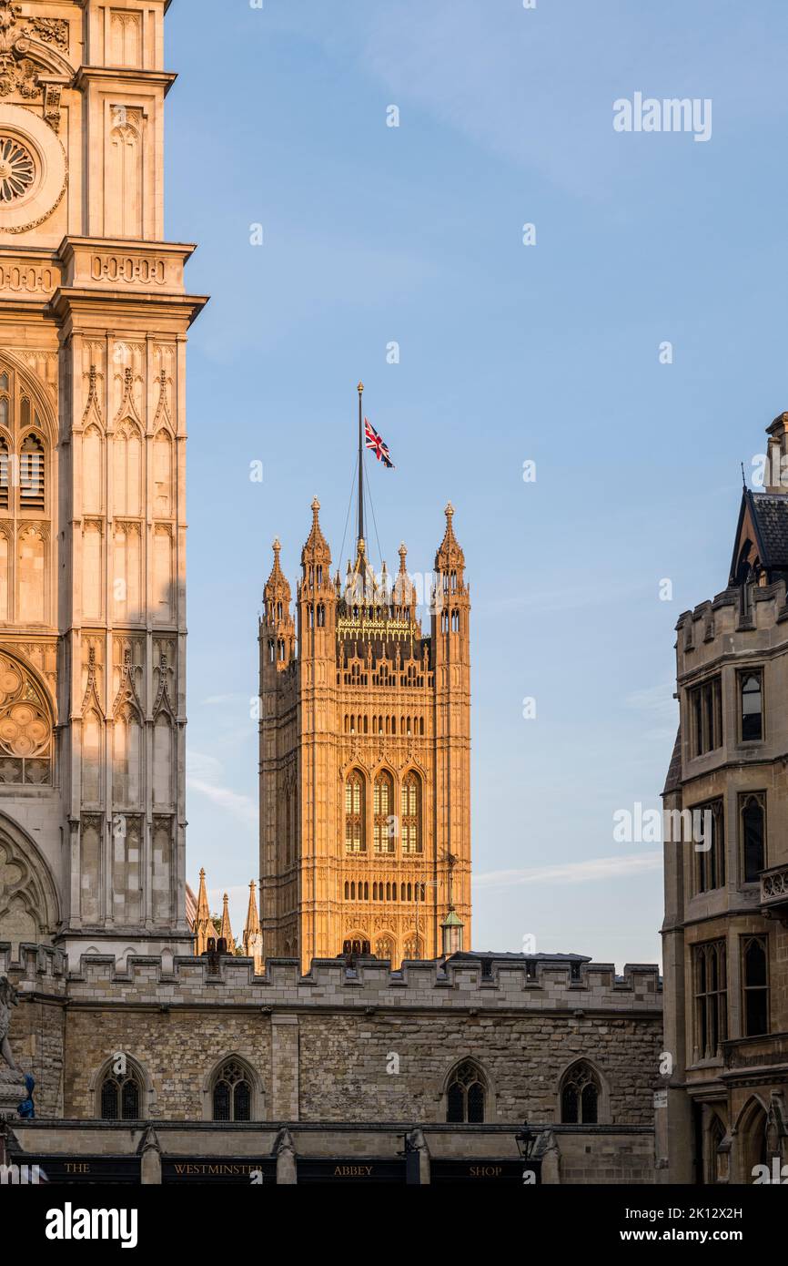 In central London the Union Jack flies at half-mast over the Victoria Tower, part of the Palace of Westminster, to mark the recent death of Queen Elizabeth II. Part of Westminster Abbey can be seen in the foreground Stock Photo