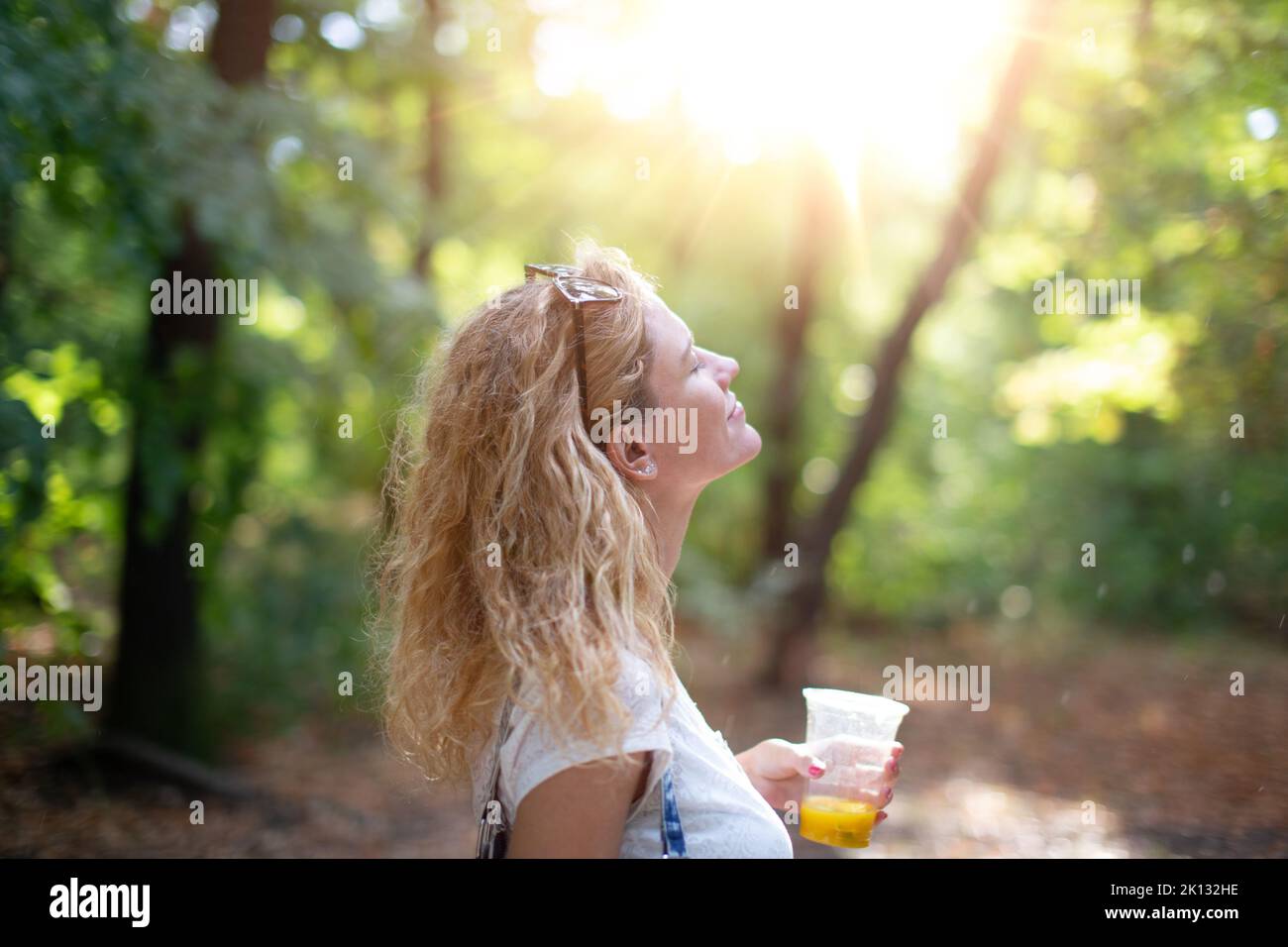 Carefree young woman enjoying sunshine after rain in nature, eyes closed Stock Photo