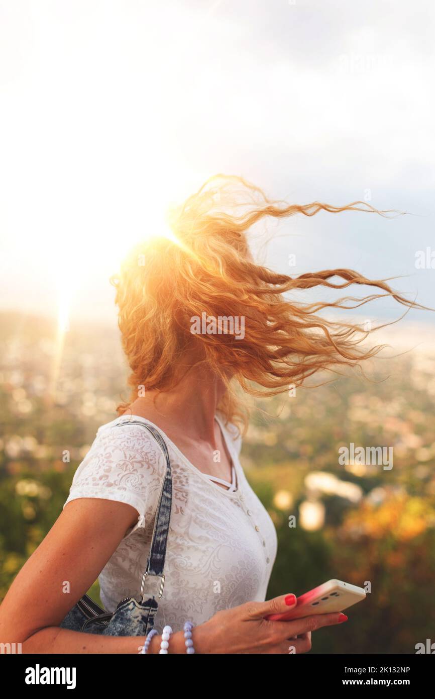 Redhead urban woman with smartphone in golden sunset book cover Stock Photo