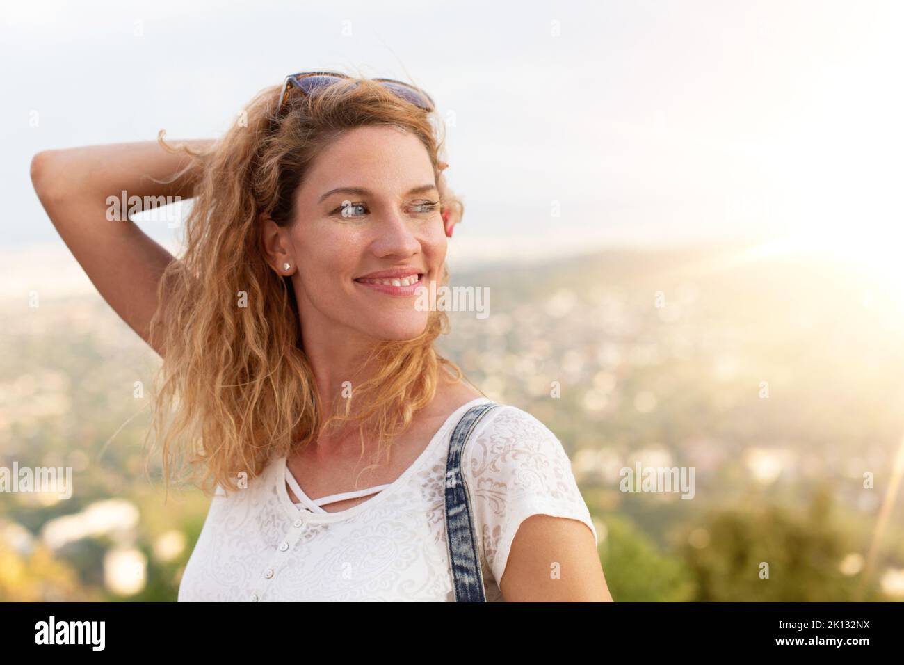 Happy young Caucasian urban woman looking away in sunset Stock Photo