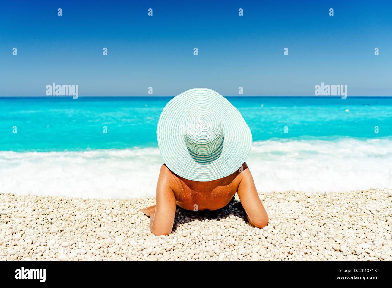 Carefree woman with straw hat sunbathing lying on a idyllic beach, Kefalonia, Ionian Islands, Greek Islands, Greece, Europe Stock Photo