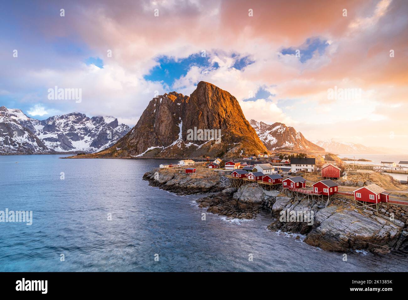 Clouds at sunrise over traditional Rorbu cottages on cliffs by the cold arctic sea, Hamnoy, Reine, Lofoten Islands, Norway, Europe Stock Photo