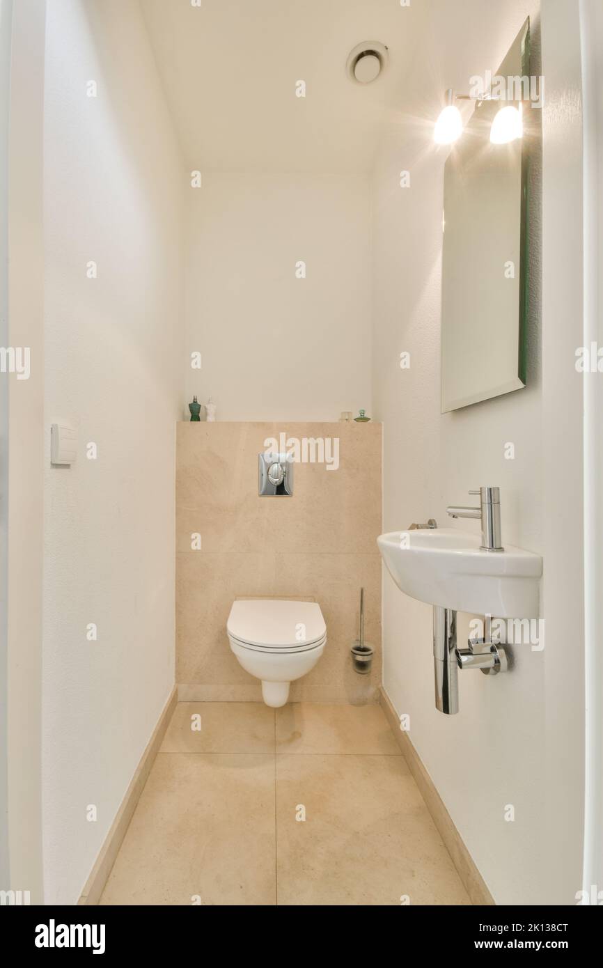 Modern toilet installed on beige wall under button and sink in restroom