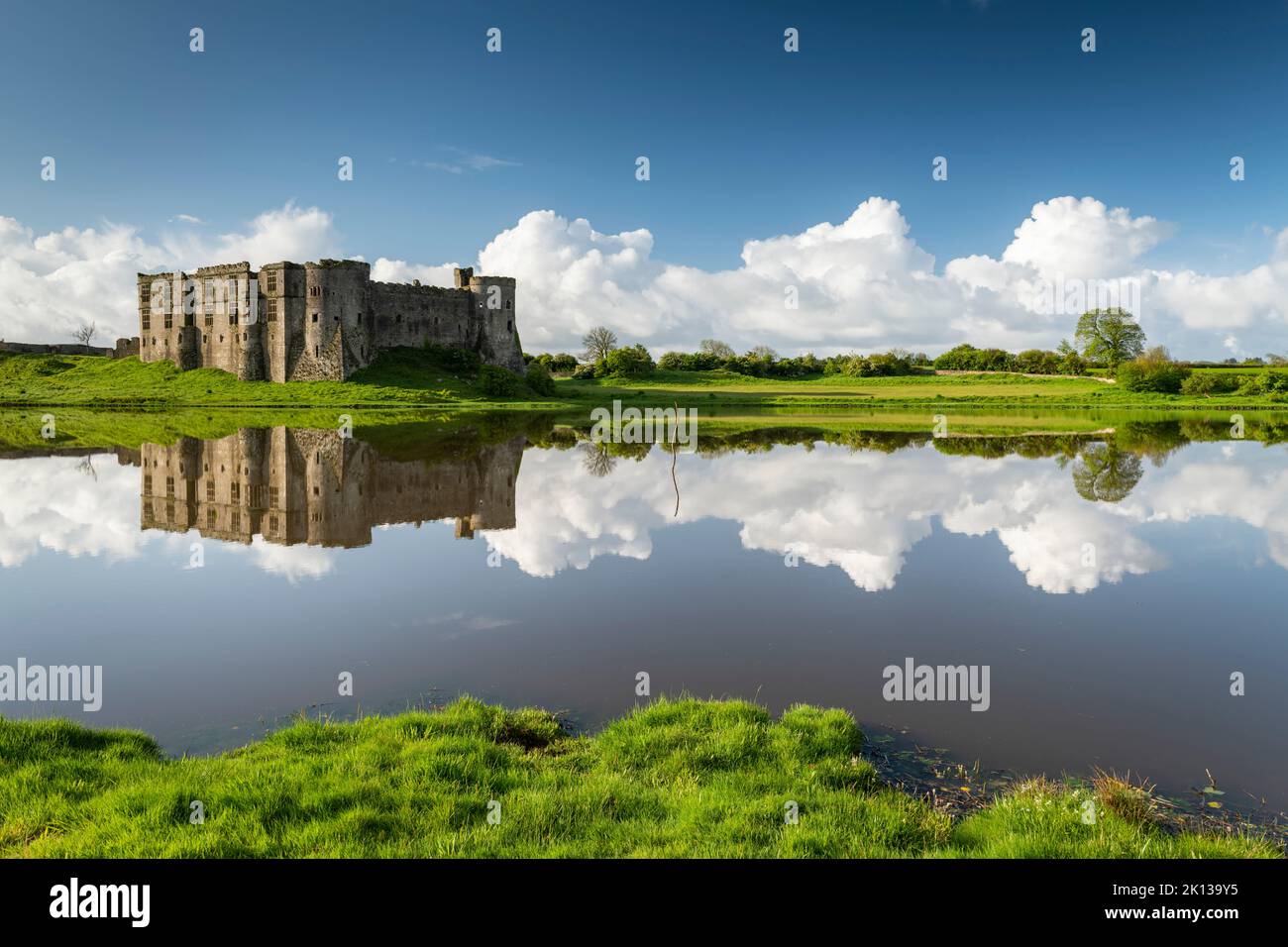 The magnificent ruins of Carew Castle reflected in the Mill Pond in spring, Carew, Pembrokeshire, Wales, United Kingdom, Europe Stock Photo