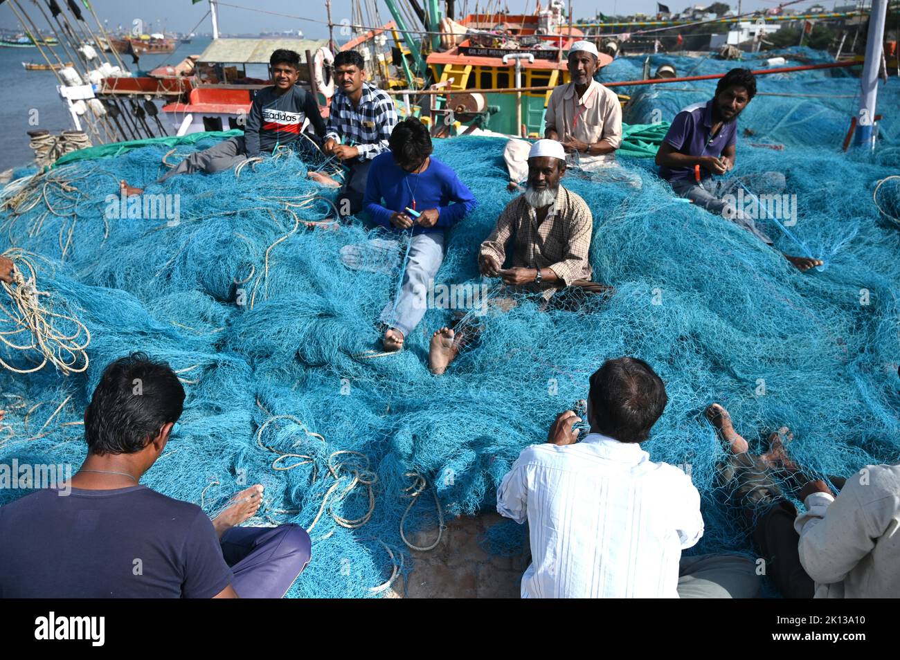 Fishing nets being mended by Muslim fishermen on the quay at Bet Dwaraka island, Dwarka, Gujarat, India, Asia Stock Photo