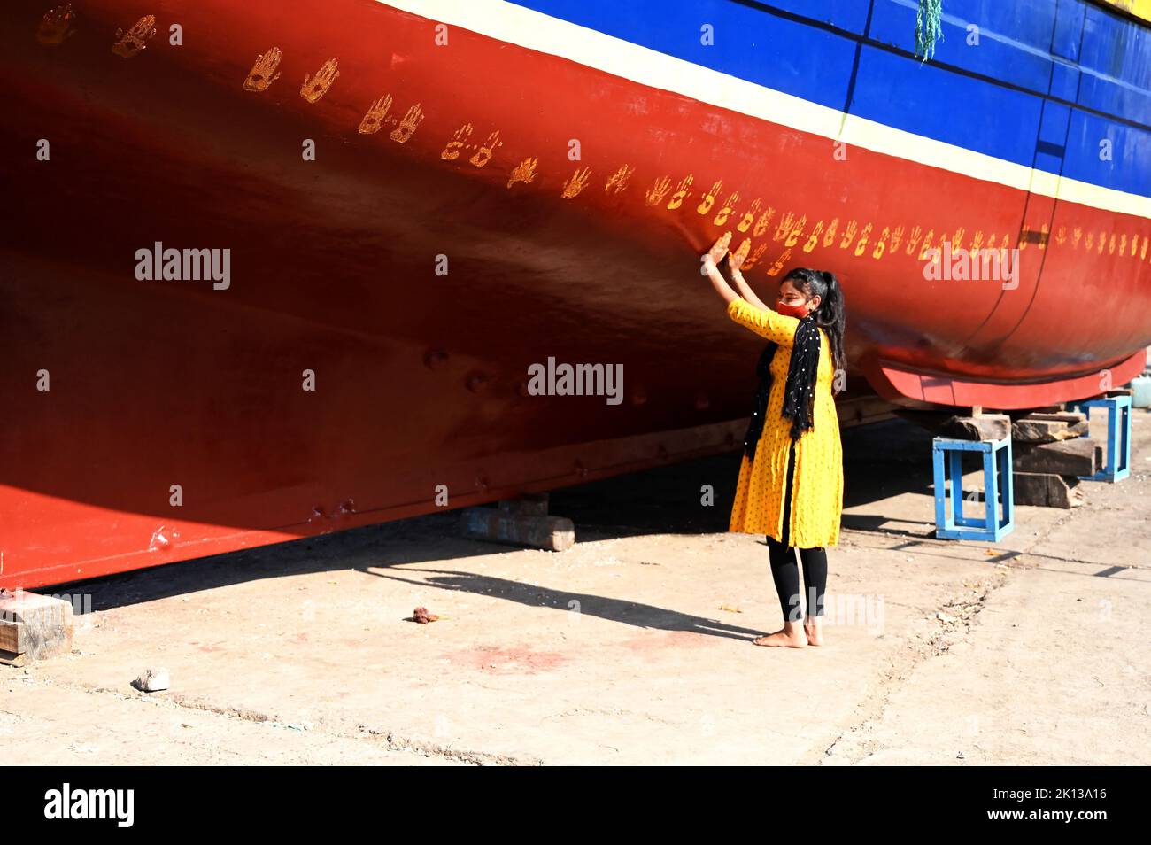 Daughter of boat owner performs puja on new boat by making hand prints along its hull prior to