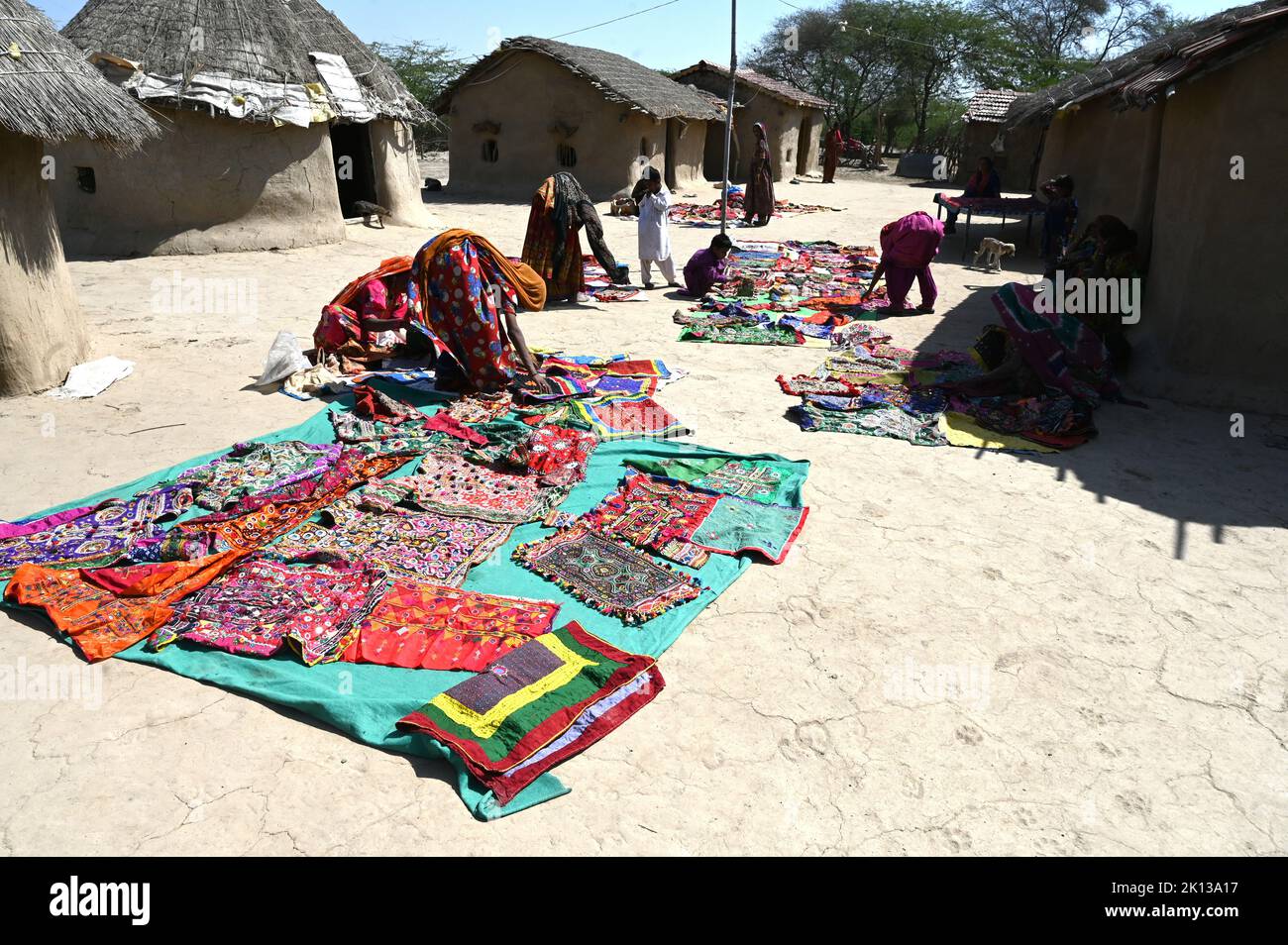 Tribal village women laying out their tribal embroidery outside mud walled houses in their tribal village, Kachchh, Gujarat, India, Asia Stock Photo