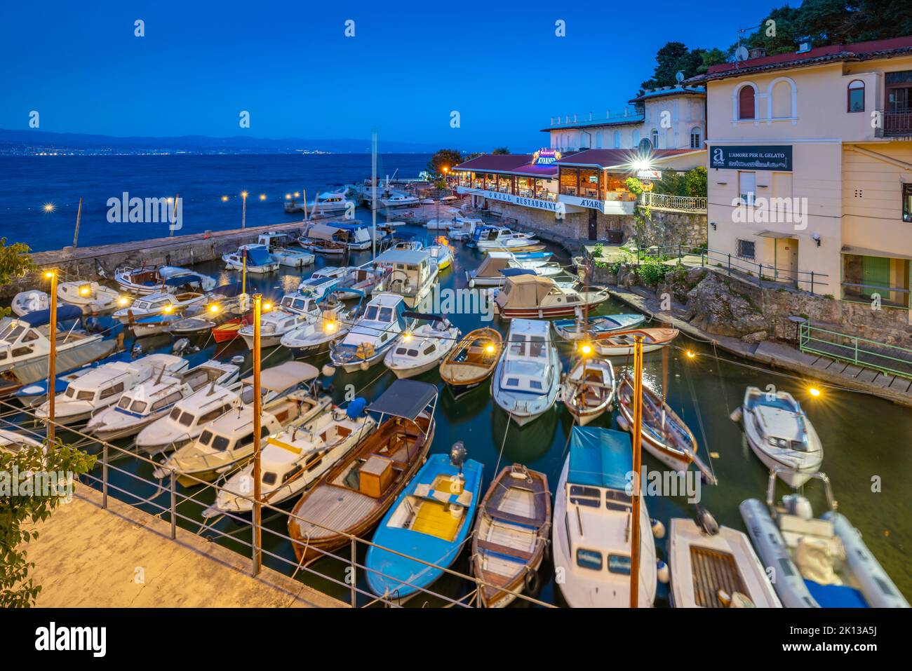 View of cafe and restaurant overlooking harbour at dusk, Lovran village, Lovran, Kvarner Bay, Eastern Istria, Croatia, Europe Stock Photo