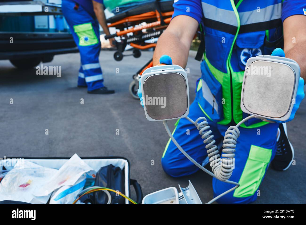 EMS paramedic holding defibrillator pads in hands during rescuing casualty and resuscitation outdoors near ambulance. Emergency medical services Stock Photo