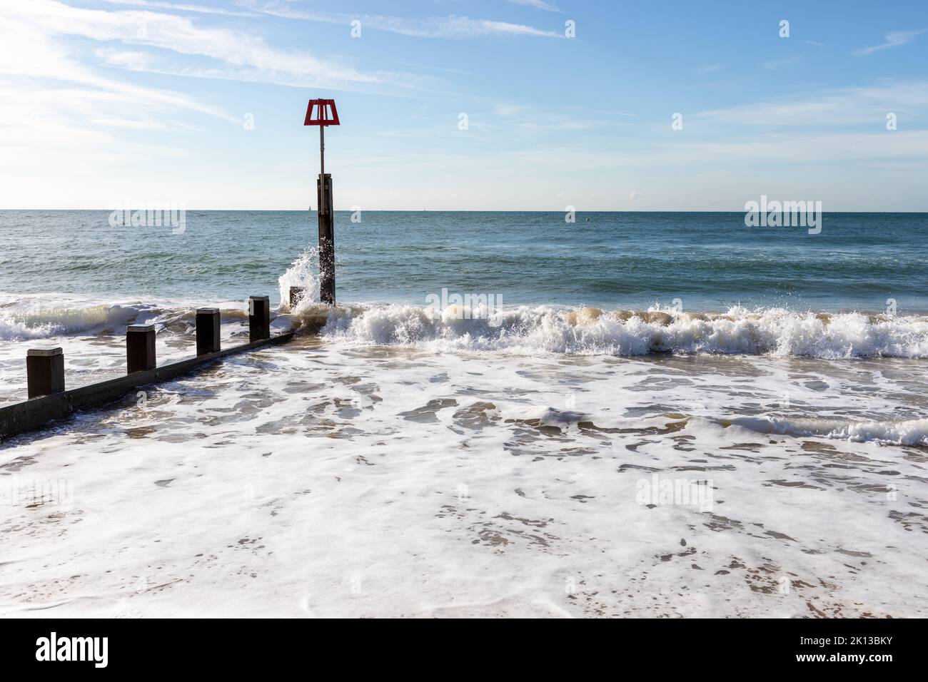 Seaside waves breaking and splashing up over a groyne marker on Bournemouth beach, Dorset, England in summertime Stock Photo