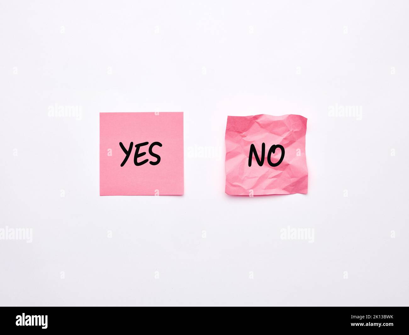 The words yes and no on pink sheets of note paper. Say or choose yes concept Stock Photo