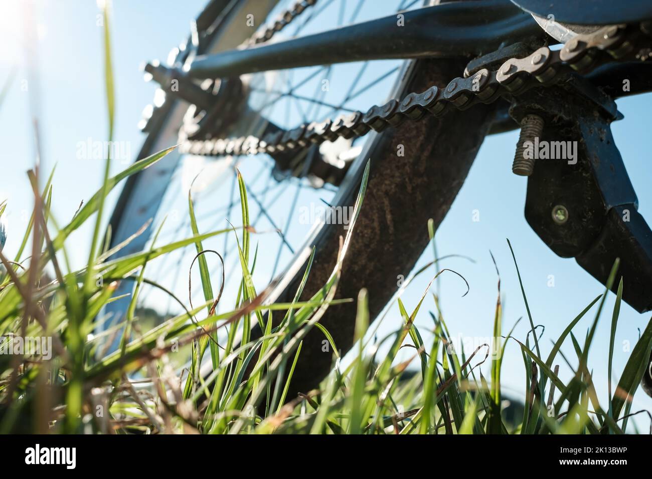 Close-up detail of a bicycle parked in a meadow, against the backdrop of the sun and blue sky. Active lifestyle concept. Bottom view. Stock Photo