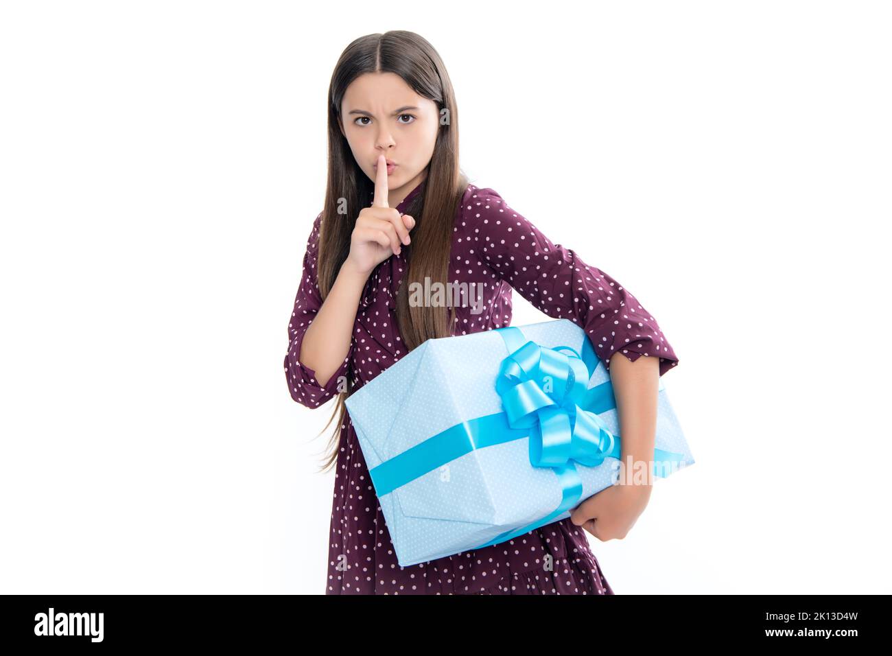 Child with gift present box on isolated studio background. Gifting for kids birthday. Serious teenager girl, shhh secret. Stock Photo