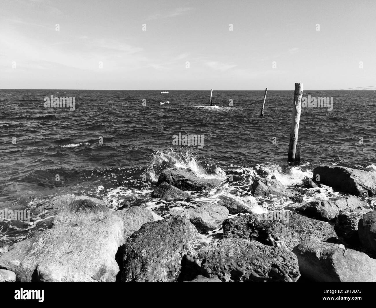 A grayscale of a rocky coast with splashing waves Stock Photo