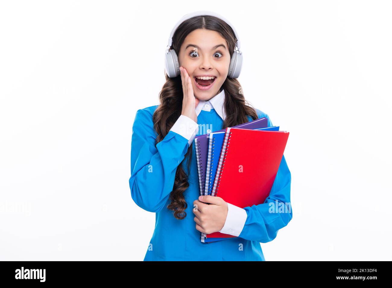 Excited face. School child girl with headphones and book isoalted on white background. Amazed expression, cheerful and glad. Stock Photo