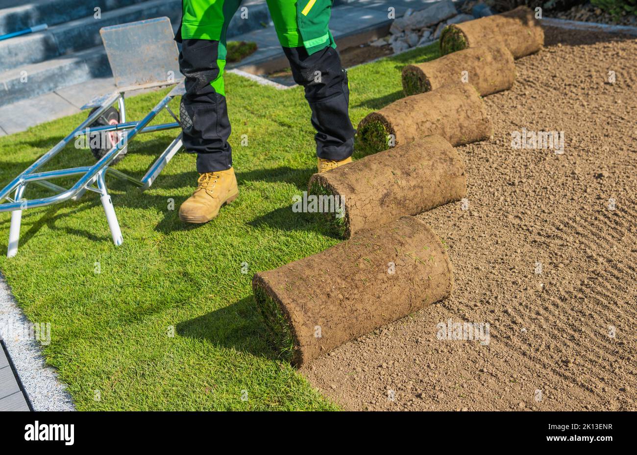Building New Natural Grass Turfs Lawn. Professional Landscaper Installing Fresh Turfs. Stock Photo