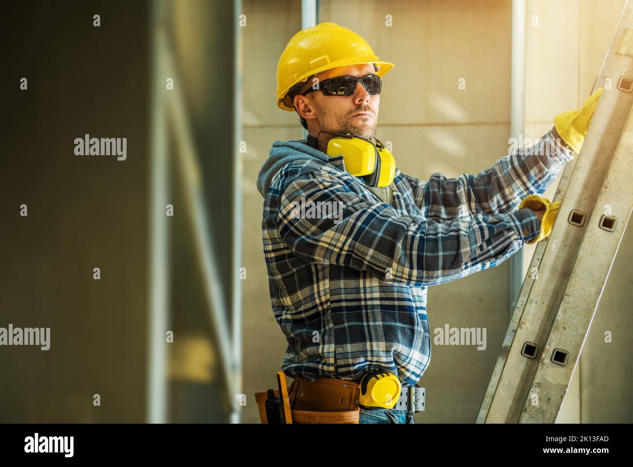 Closeup of Caucasian Middle Aged Contractor Unfolding His Extension Ladder at a Construction Site of New Commercial Building. Industrial Theme. Stock Photo