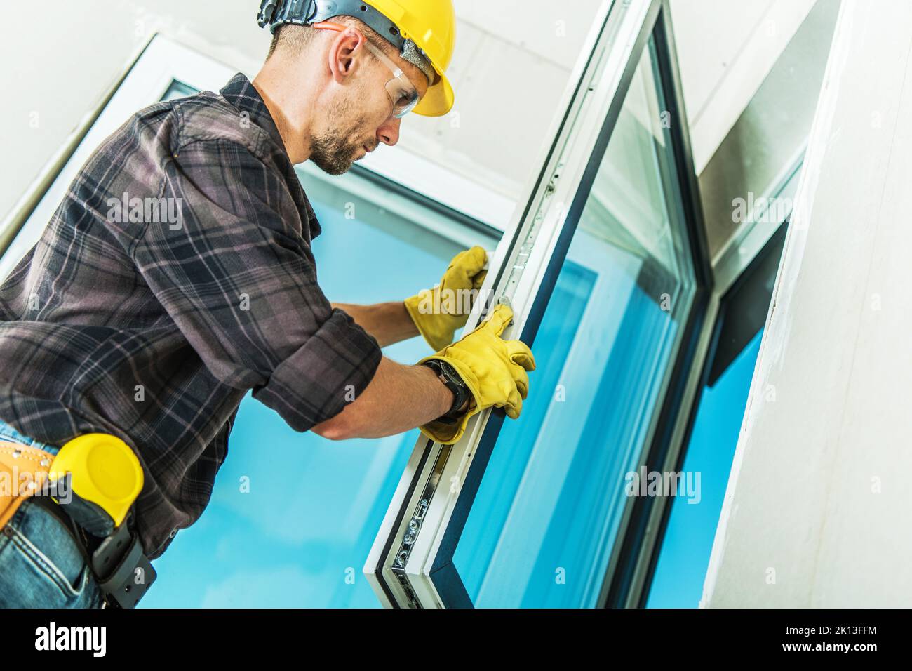 Caucasian Middle Aged Professional Contractor Checking Locks and Handle Assembly During Windows Installation Process in Freshly Built Residential Hous Stock Photo