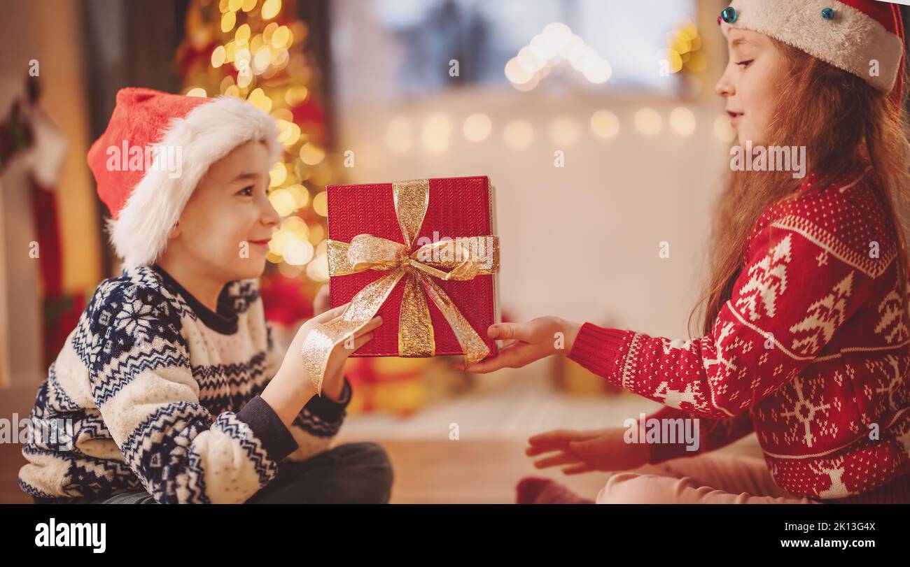 Boy giving red present box to cute girl Stock Photo