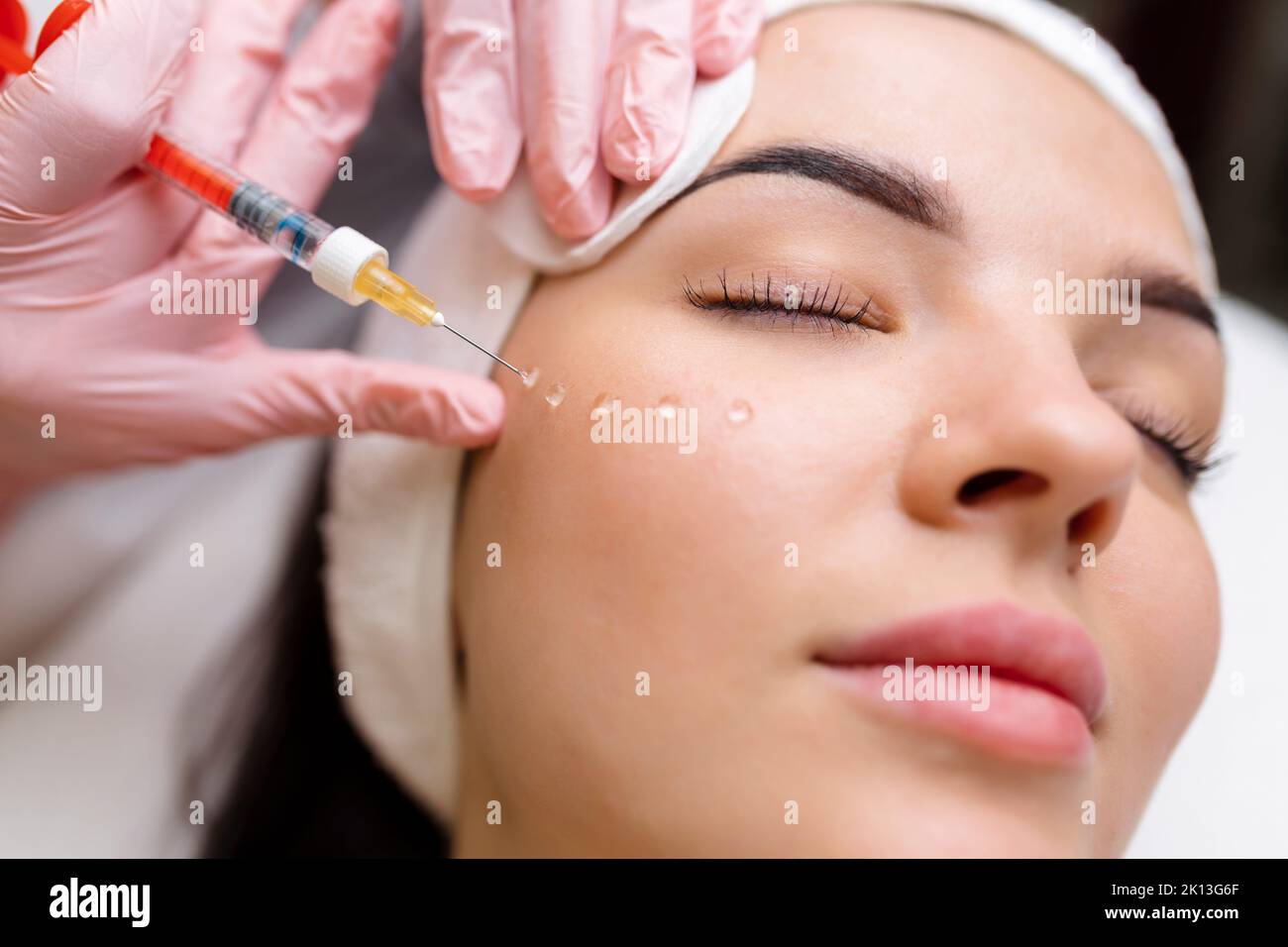 Cosmetologist makes rejuvenating anti wrinkle injections on the face of a beautiful woman. Female aesthetic cosmetology in a beauty salon. Stock Photo