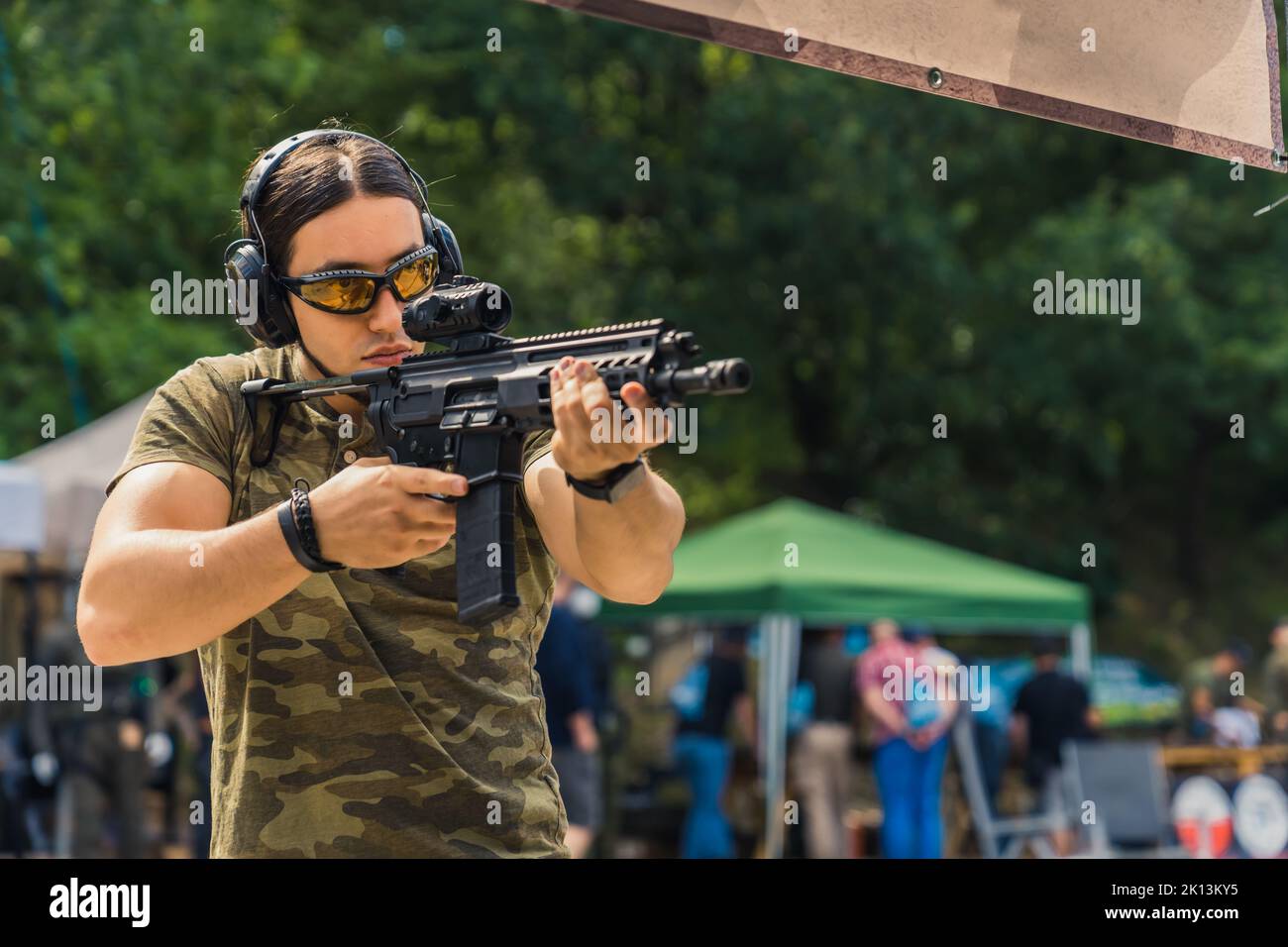 muscular Caucasian man looking through a rifle loupe at the shooting range, medium shot. High quality photo Stock Photo