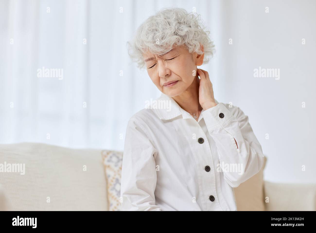 Japanese senior in pain on the sofa Stock Photo