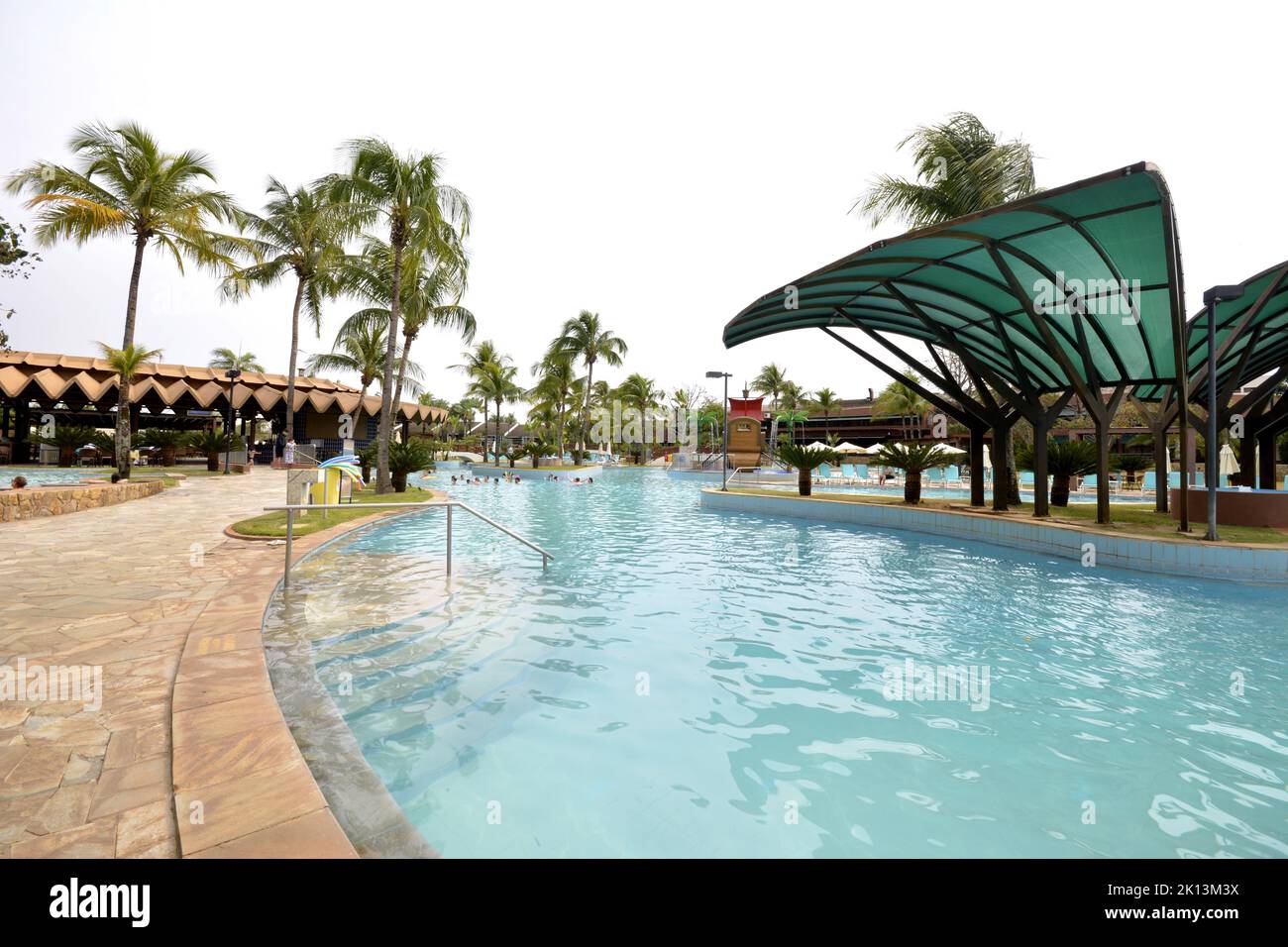 Tourists at a luxury resort pool with sun loungers in the background on a cloudy blue sky day. panoramic. Stock Photo