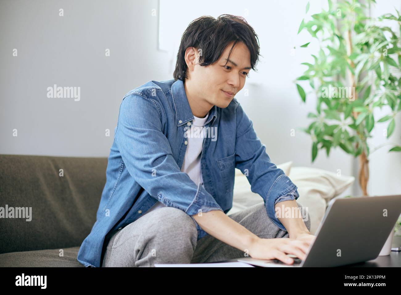 Japanese Man Using Computer Japanese man using laptop on the sofa Stock Photo - Alamy