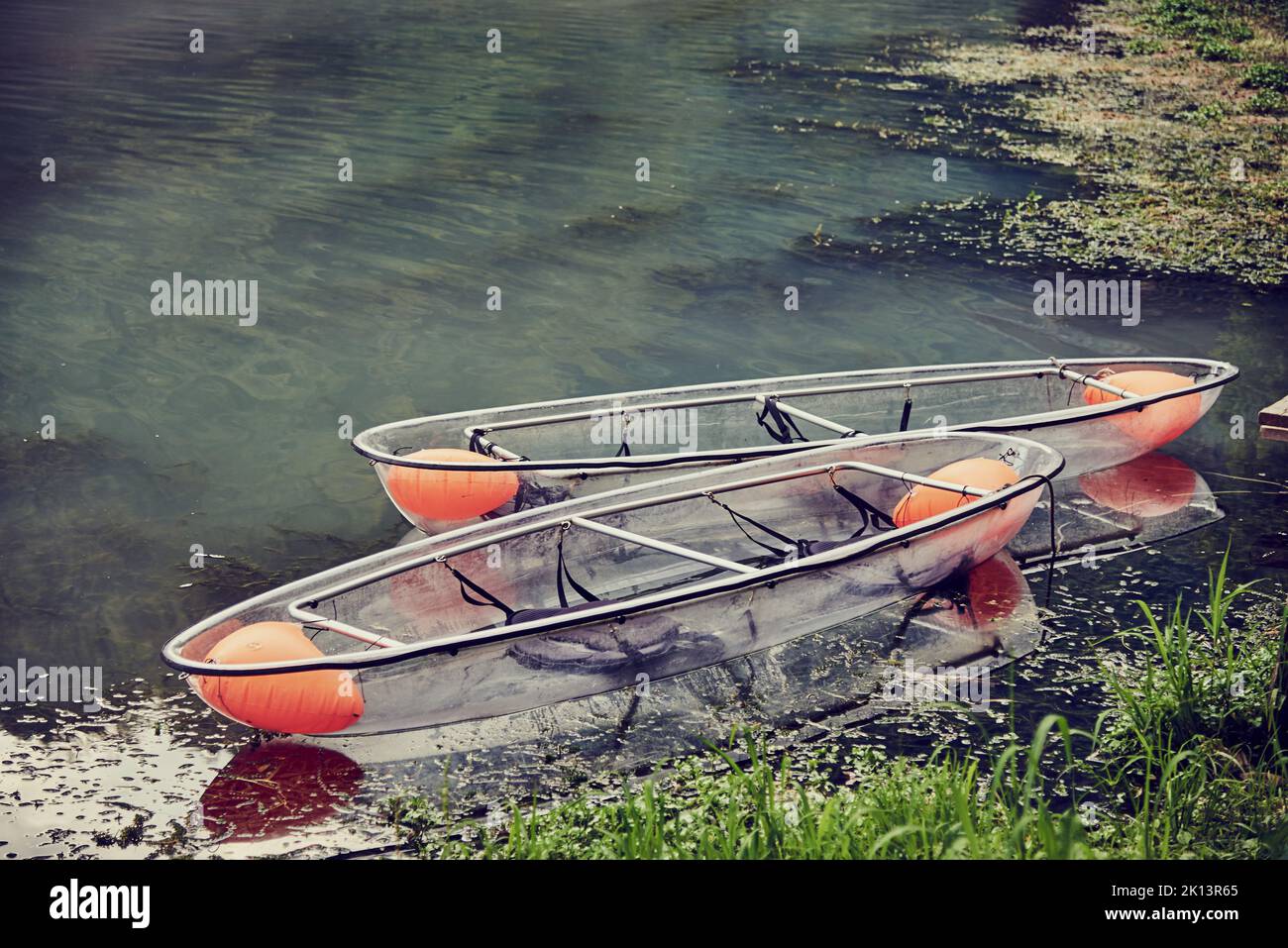 Two transparent boats on the lake near the shore waiting for passengers. Stock Photo
