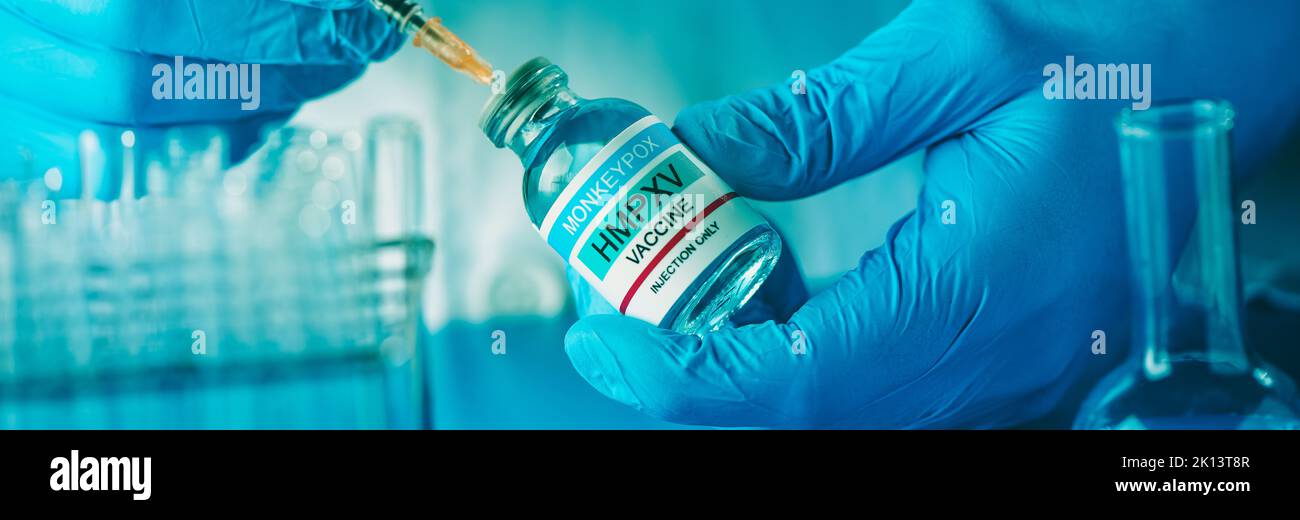 a laboratory or healthcare worker man fills a syringe with a simulated monkeypox vaccine from a vial, in a panoramic format to use as web banner or he Stock Photo