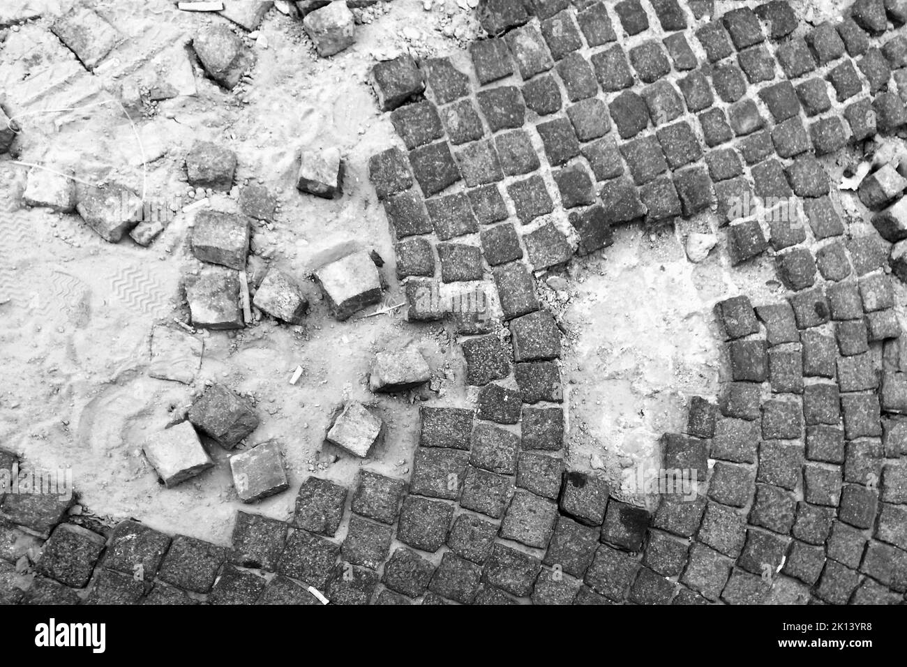 A grey closeup of a part of a paved street with dilapidated tiles Stock Photo