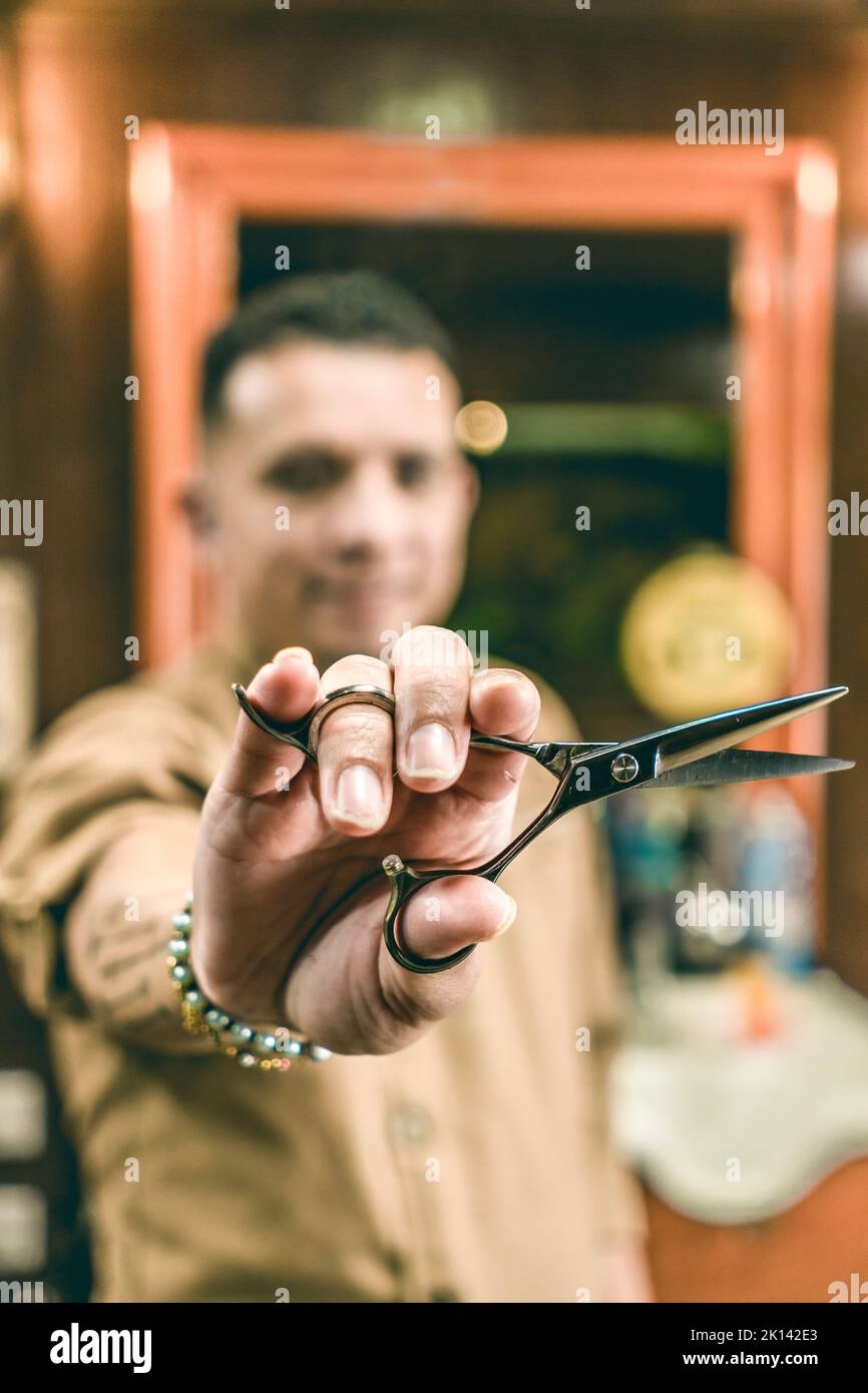 Defocused young barber showing scissors while working in salon Stock Photo