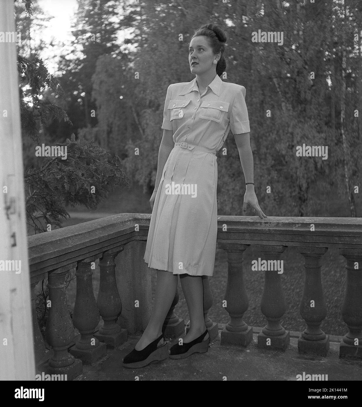 Women's fashion in the 1940s. A young woman photographed for a ladies magazine to show the women's fashion of 1945. The female model is wearing a dress with a belt decorated with pockets and buttons. Sweden 1945.  Kristoffersson Ref R6-3 Stock Photo