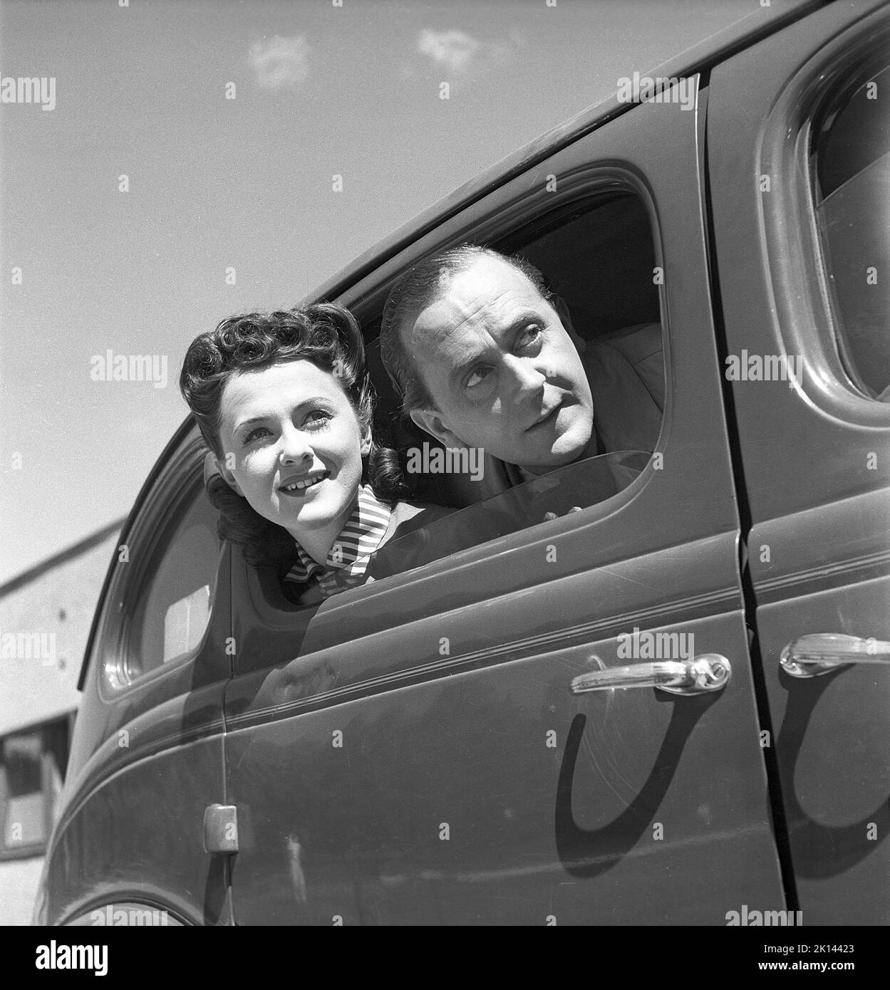 Couple in the 1940s. A man and a woman looks out of the side window of car as if they have seen something interesting. They are actors Lillebil Kjellén and Sweden filming a movie in 1945. Sweden Kristoffersson ref  O103-1 Stock Photo