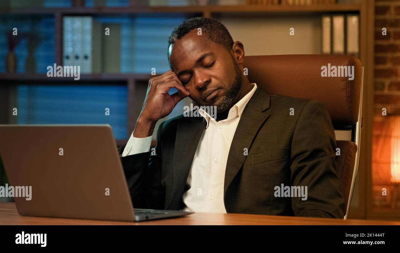 Tired sleepy businessman bored at work falling asleep at office desk sleeping at workplace feeling overworked overloaded male professional manager Stock Photo